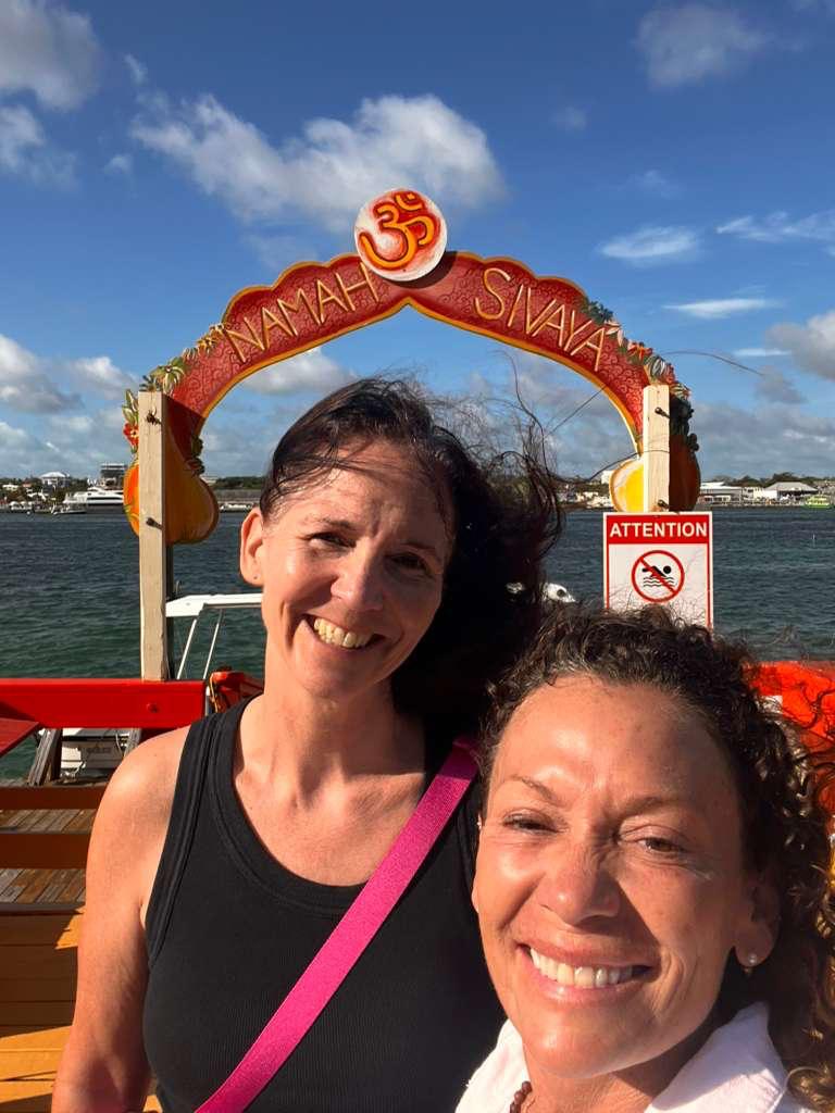 Two students smiling beneath the Sivananda arch by the water