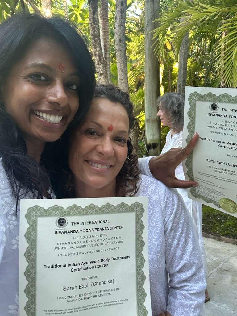 Two students smiling with their Sivananda Ayurveda certificates