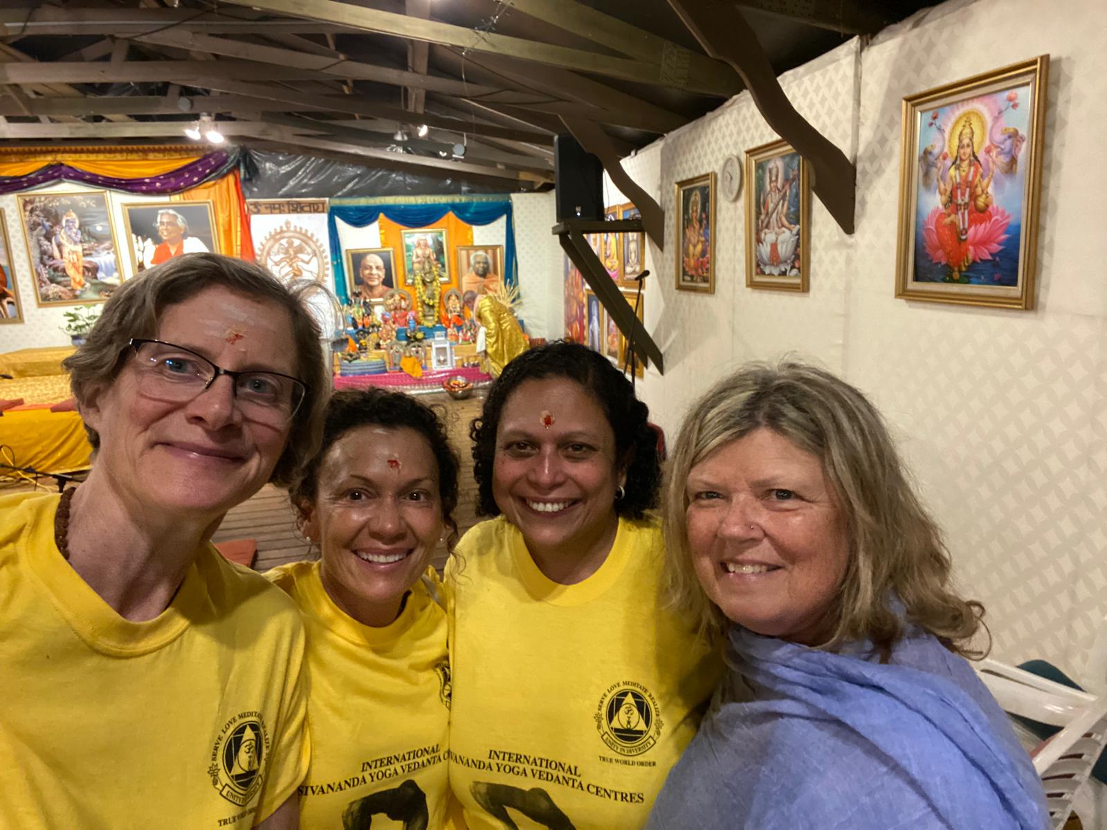 Four smiling members of the Sangha together inside the temple