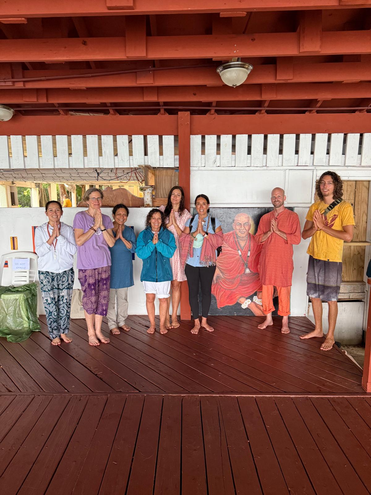 Members of the MIP community gathered in namaste beside an image of the master
