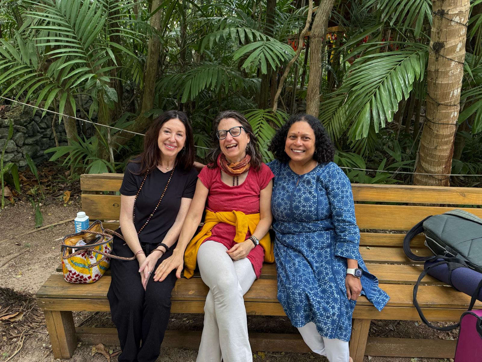 Three members of the Sangha laughing together on a garden bench